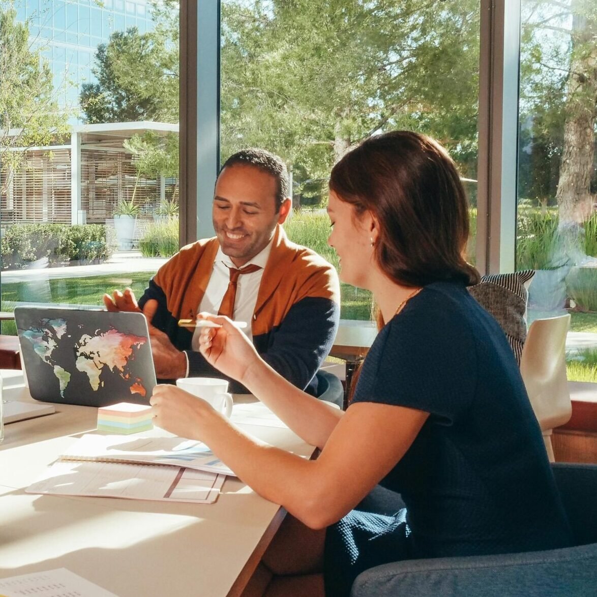 Three colleagues brainstorming with laptops in a well-lit office.